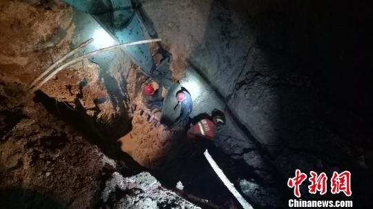 消防员和村民冒着危险继续下井救援。 郑振盛 摄