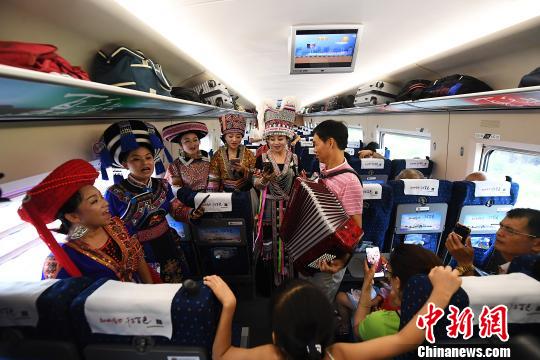 图为广西少数民族同胞在首发列车上向游客推介民族风情。　俞靖 摄